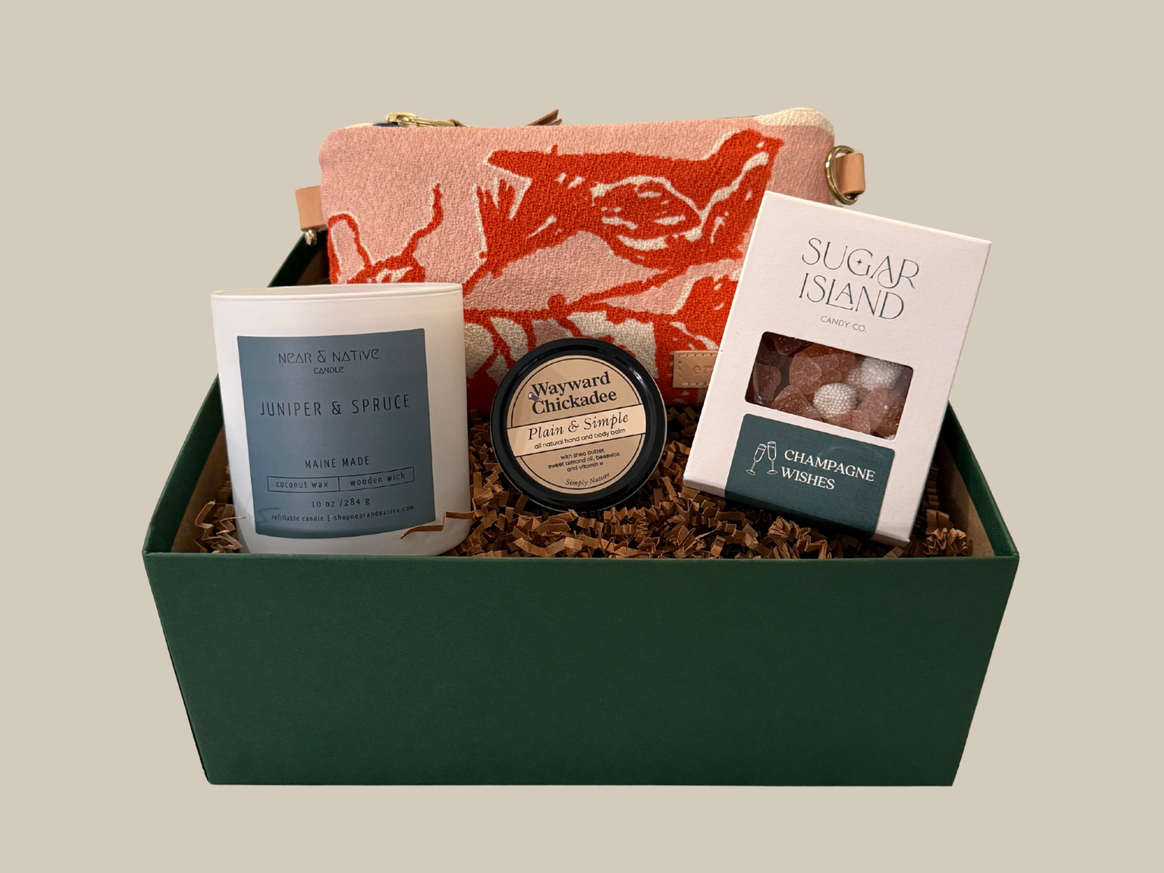 Gift basket with a candle, pouch, and book on a neutral background