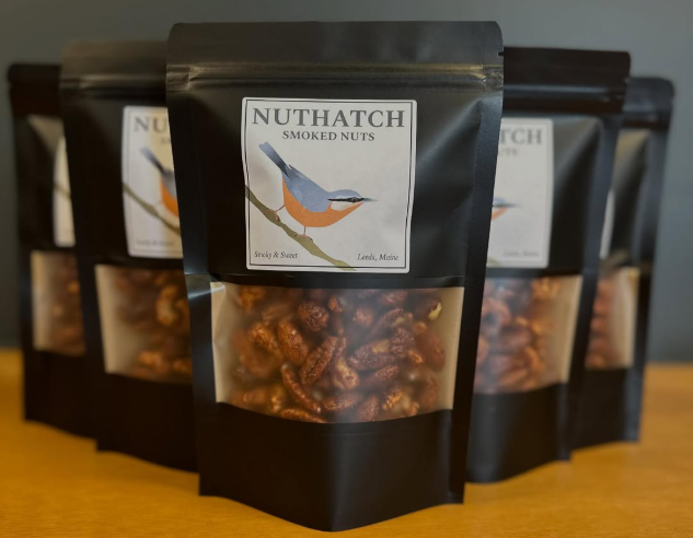 Packaged smoked nuts with Nuthatch Smoked Nuts label on a wooden surface.